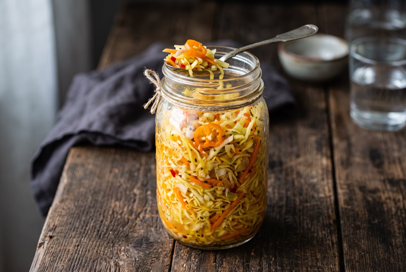 Glass jar of Haitian pikliz packed with shredded cabbage, carrot and sliced Scotch bonnet peppers