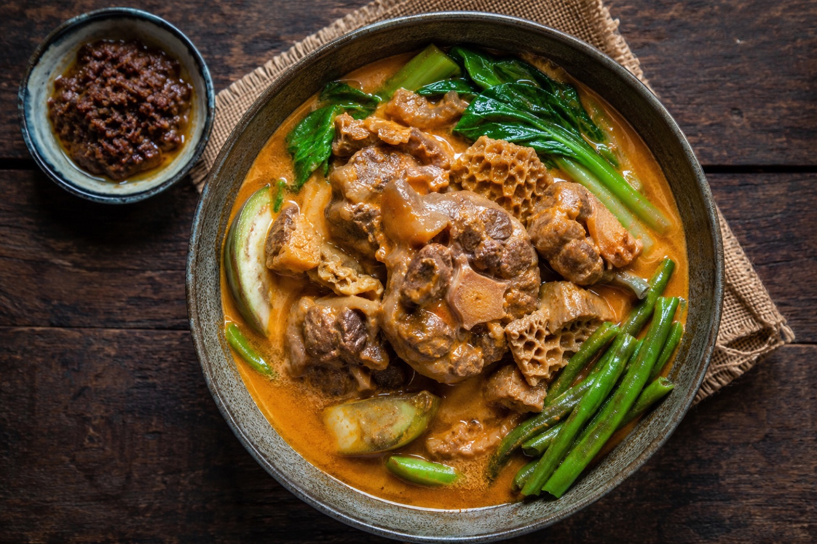 Kare-kare in an earthenware pot: oxtail in thick orange peanut sauce topped with eggplant, long beans and bok choy