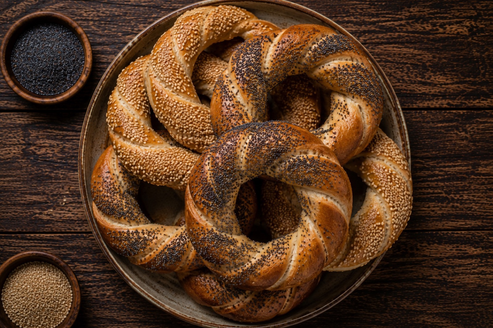 Twisted Kraków bread rings covered in poppy and sesame seeds, glossy from being boiled before baking