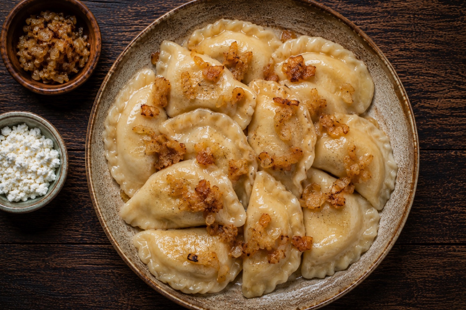 Golden pan-fried pierogi ruskie dumplings topped with caramelized onions and sour cream