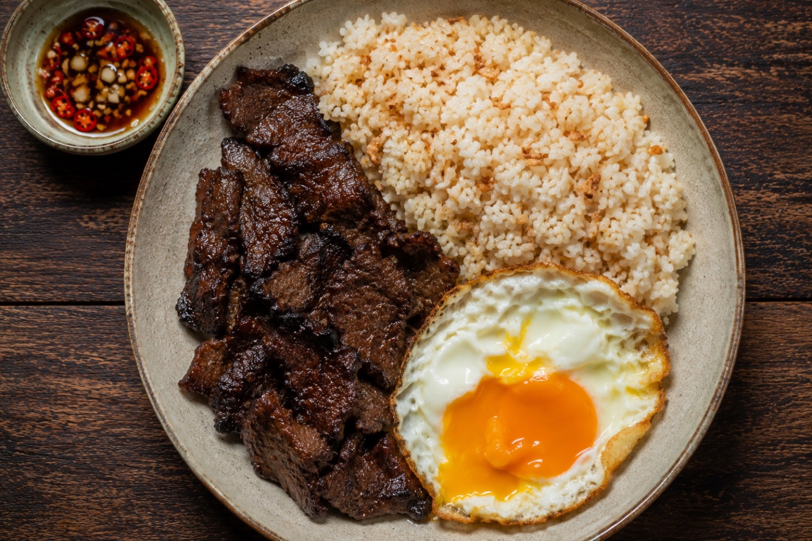 Tapsilog plate with caramelised beef tapa, garlic fried rice topped with garlic chips and a sunny side up egg